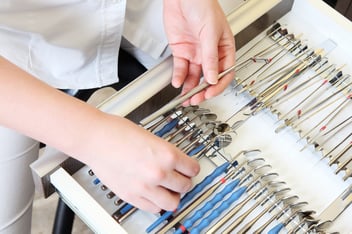 hands preparing dental tools on a tray