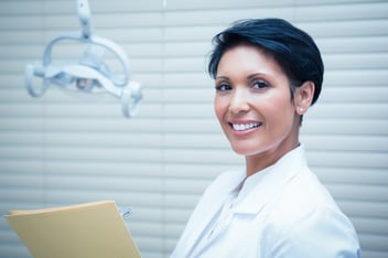 smiling female dentist holding reports