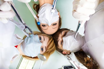 three dentists standing with their heads together looking down
