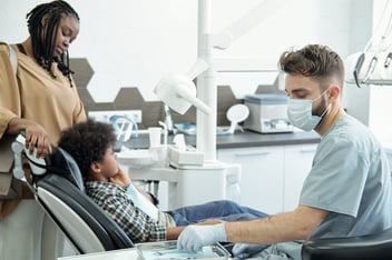 dentist with a child patient and their mother