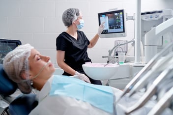 dentist pointing to a screen while patient is sedated