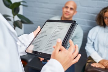 patient holding a tablet with a patient intake form