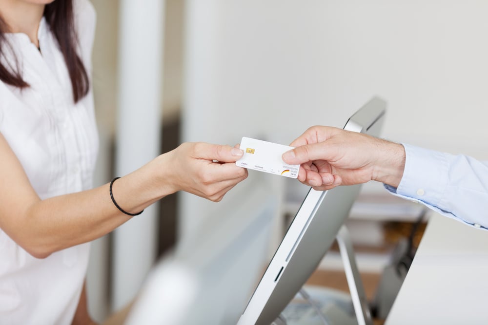 Patient handing card to receptionist for payment.