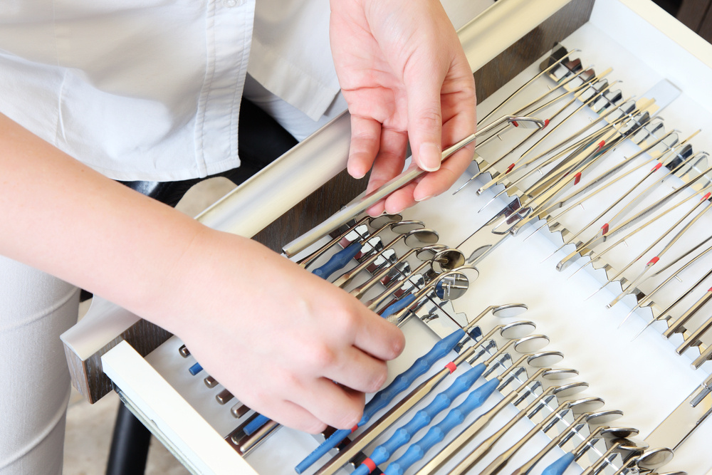 hands preparing dental tools on a tray
