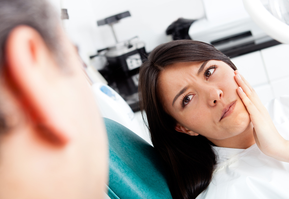 Patient holding their cheek and looking at the dentist
