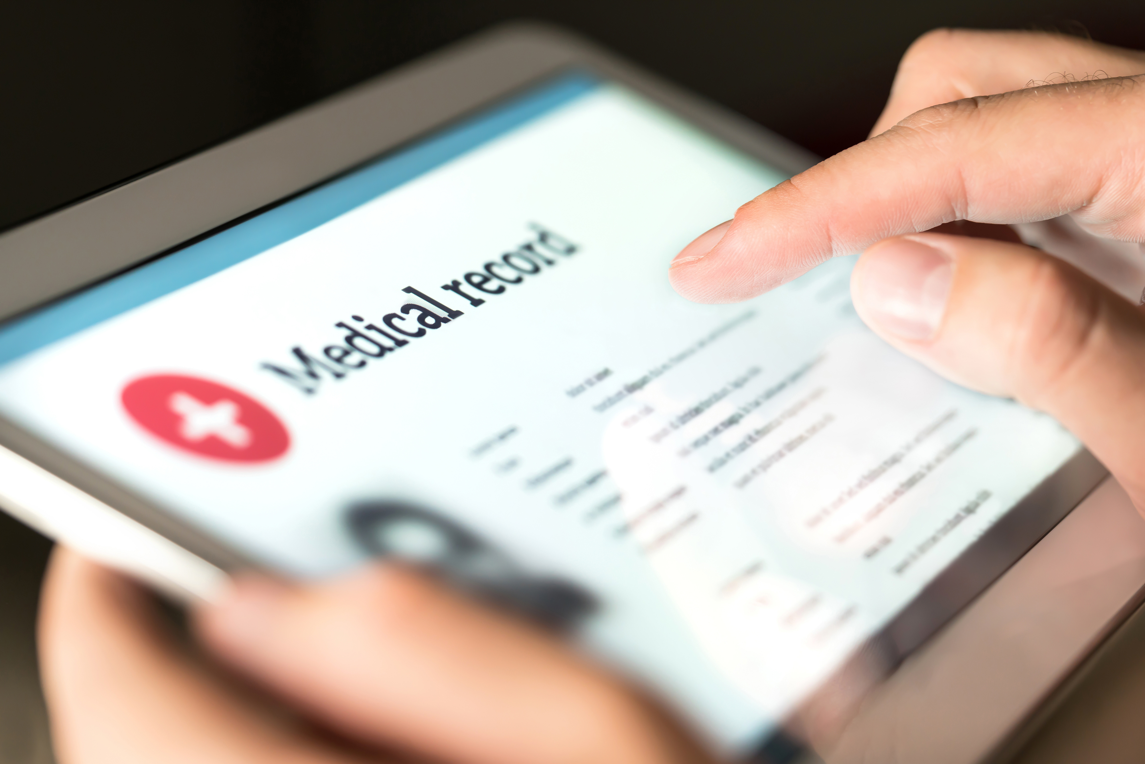 hands on a tablet showing patient medical records