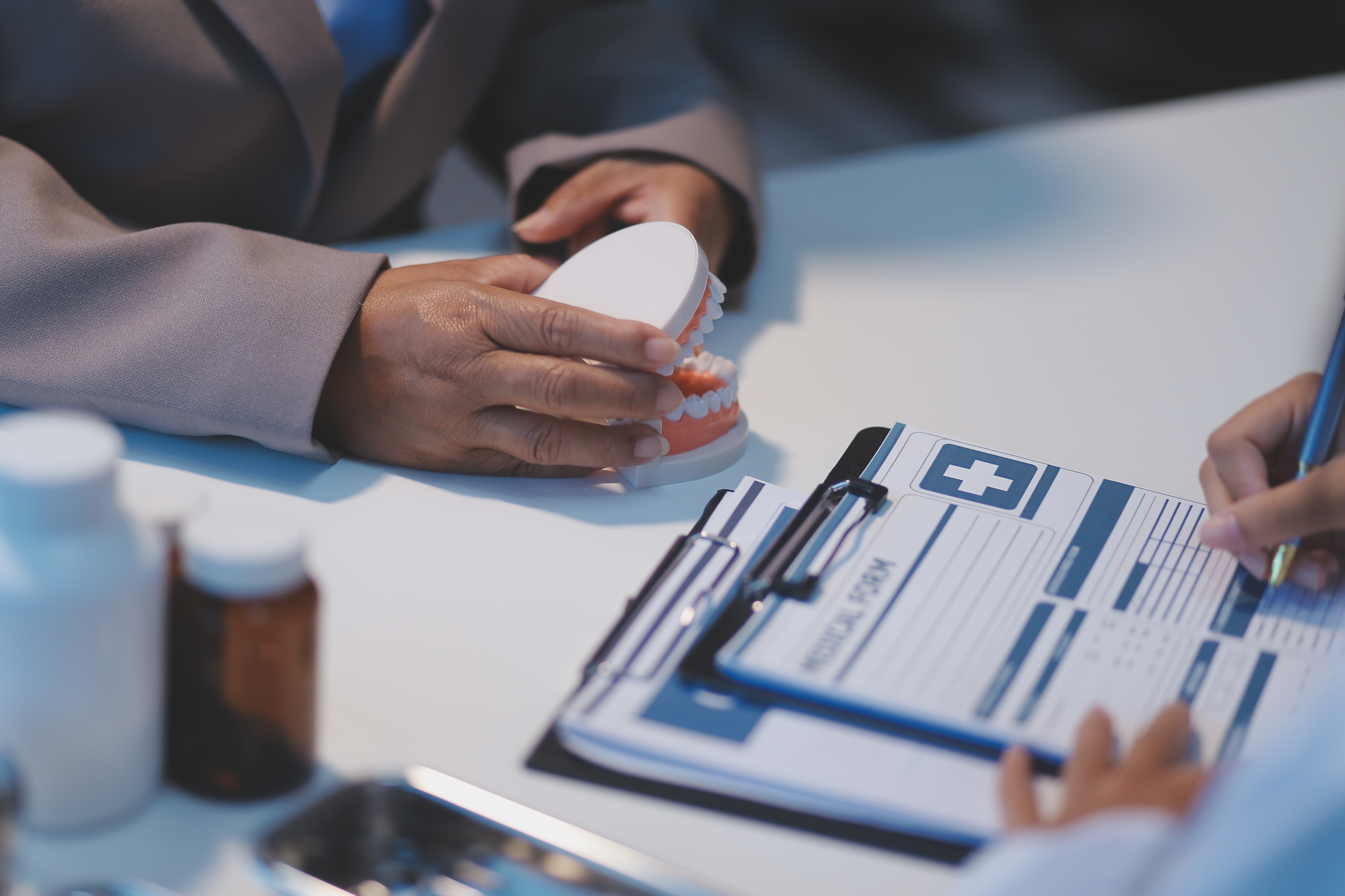hands holding a teeth mold and a dental form