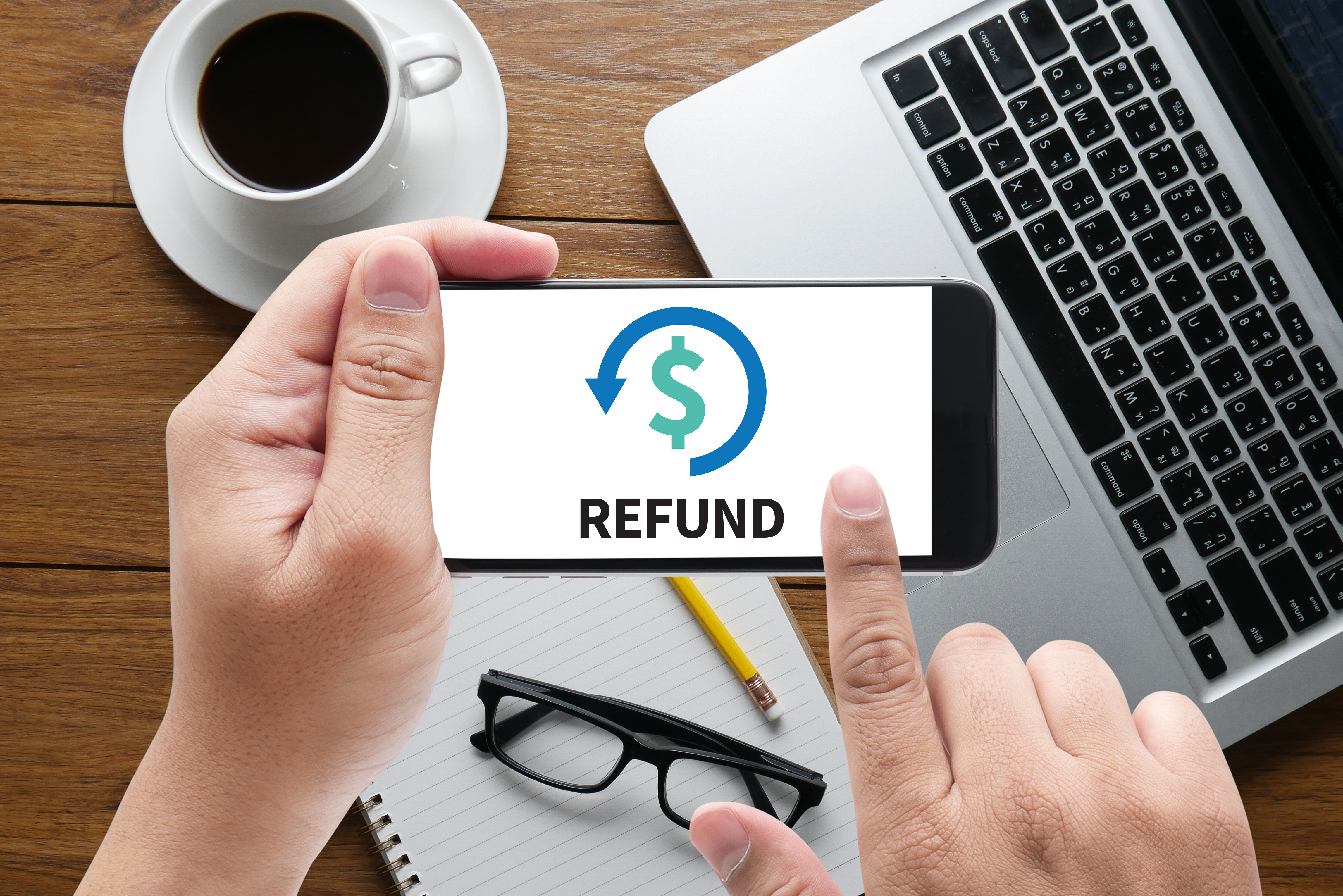 Hands holding a cellphone with the word "refund" on the screen.